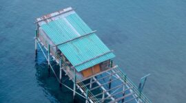 Rumah-rumah panggung di atas permukaan laut menjadi pemandangan khas komunitas pesisir Indonesia, sebuah cara hidup yang kini menghadapi tekanan ganda dari perubahan iklim dan keterbatasan kebijakan perlindungan wilayah adat laut.