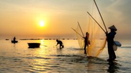 Seorang nelayan tradisional melaut menggunakan perahu kayu saat matahari terbit di kawasan pesisir Indonesia, menggambarkan keterikatan erat masyarakat bahari dengan alam laut.