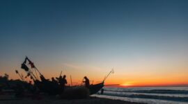 Seorang nelayan melintasi perairan dangkal dengan perahu kayu tradisional saat matahari terbit di kawasan pesisir Indonesia. Aktivitas harian ini memperlihatkan keharmonisan antara manusia dan laut yang terus terjaga secara turun-temurun.