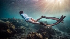 Seorang penyelam lokal dengan cermat merawat fragmen karang baru pada media transplantasi bawah laut sebagai bagian dari upaya restorasi ekosistem pesisir di perairan Nusantara.