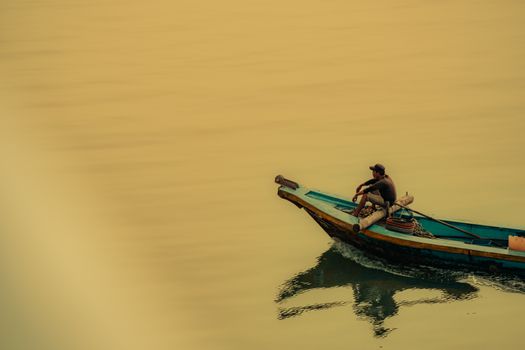 Seorang nelayan tradisional menyiap jaringan perahu kayunya di pesisir pantai Indonesia saat matahari terbenam. Kehidupan masyarakat pesisir tetap menyatu erat dengan ritme alam dan laut Nusantara.