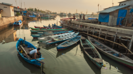 Deretan perahu tradisional milik warga nelayan yang berlabuh rapi di pesisir pantai saat matahari terbit, mencerminkan harmoni kehidupan bahari Nusantara.
