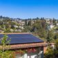 Instalasi panel surya pada atap rumah di kawasan perkotaan yang memanfaatkan sinar matahari sebagai energi alternatif ramah lingkungan.