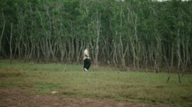 Seorang relawan sedang menancapkan bibit mangrove di kawasan pesisir berlumpur untuk memperkuat dinding benteng alami pantai dari ancaman abrasi laut.