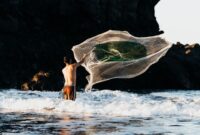 Seorang nelayan tradisional di perairan Indonesia sedang menebarkan pancing ulur yang ramah lingkungan untuk menangkap ikan secara selektif tanpa merusak terumbu karang.