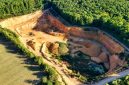 Lahan bekas penambangan terbuka di wilayah pedalaman Indonesia yang mengubah lanskap hutan hujan tropis menjadi galian tanah merah, mencerminkan harga ekologis yang harus dibayar demi pemenuhan komoditas mineral global.