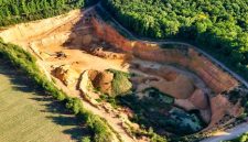 Lahan bekas penambangan terbuka di wilayah pedalaman Indonesia yang mengubah lanskap hutan hujan tropis menjadi galian tanah merah, mencerminkan harga ekologis yang harus dibayar demi pemenuhan komoditas mineral global.