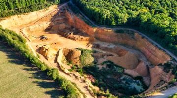 Lahan bekas penambangan terbuka di wilayah pedalaman Indonesia yang mengubah lanskap hutan hujan tropis menjadi galian tanah merah, mencerminkan harga ekologis yang harus dibayar demi pemenuhan komoditas mineral global.
